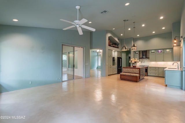 kitchen featuring wall chimney range hood, sink, decorative backsplash, decorative light fixtures, and stainless steel range oven