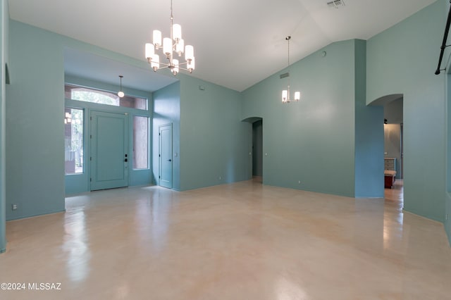 foyer entrance with concrete flooring, high vaulted ceiling, and a notable chandelier