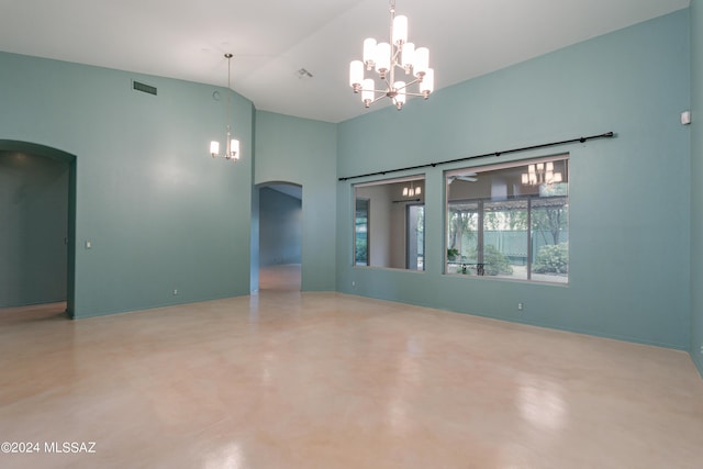 empty room with high vaulted ceiling, concrete flooring, and a notable chandelier