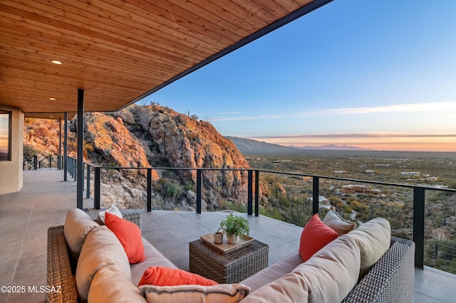 balcony at dusk featuring outdoor lounge area, a mountain view, and a patio area