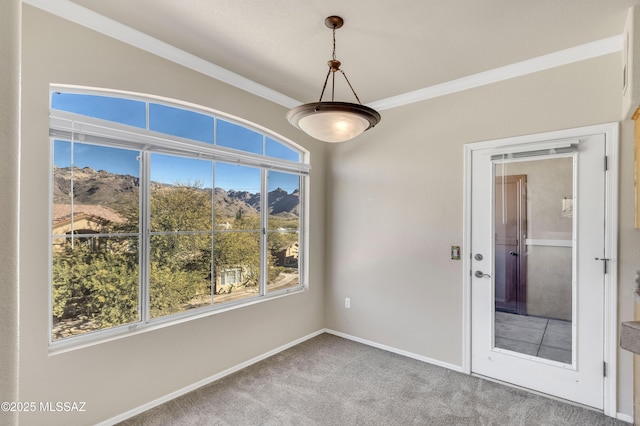 carpeted empty room with a wealth of natural light, crown molding, and a mountain view