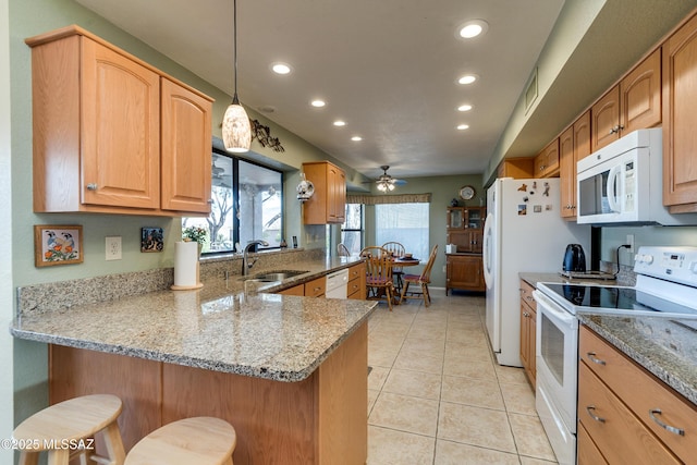 kitchen with sink, a breakfast bar area, light stone counters, kitchen peninsula, and white appliances