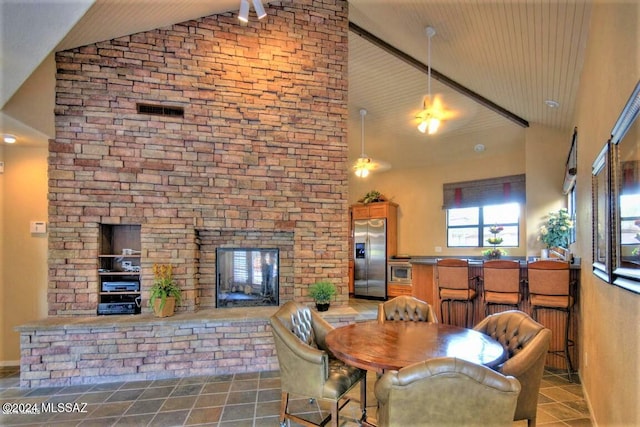 dining area featuring high vaulted ceiling and a fireplace