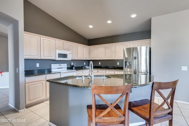 kitchen with light tile patterned floors, white appliances, a kitchen island with sink, and sink