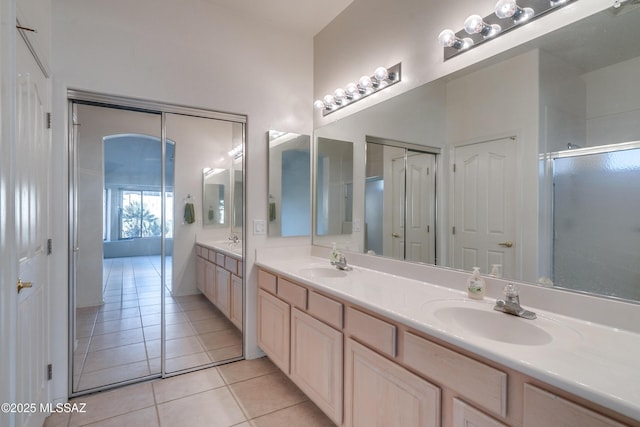 bathroom featuring tile patterned floors, a shower with door, and vanity