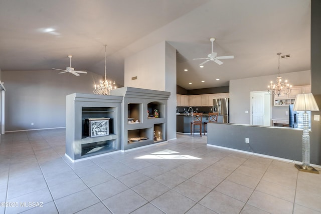 unfurnished living room with ceiling fan with notable chandelier, built in shelves, vaulted ceiling, and light tile patterned floors