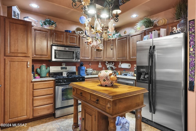 kitchen featuring light tile patterned floors, stainless steel appliances, and hanging light fixtures