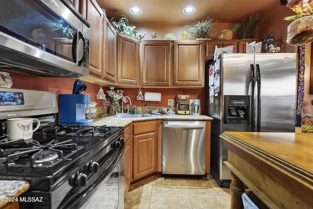 kitchen featuring light tile patterned flooring, light stone counters, sink, and appliances with stainless steel finishes