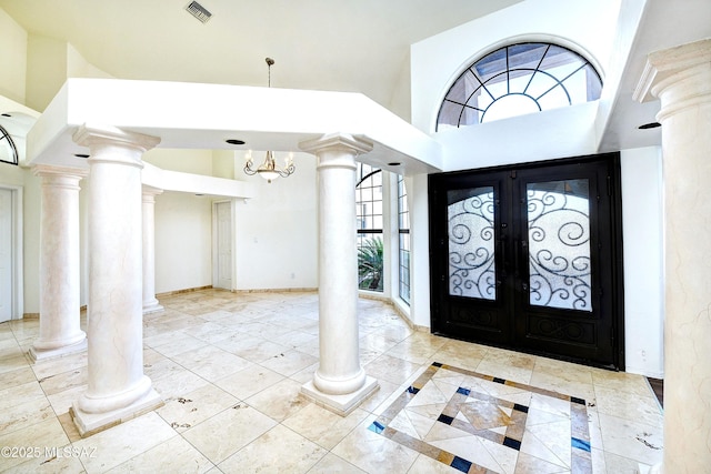 foyer entrance featuring french doors, a towering ceiling, and an inviting chandelier