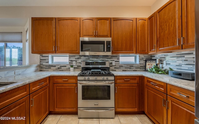 kitchen with decorative backsplash, light tile patterned flooring, light stone countertops, and stainless steel appliances