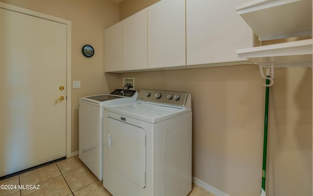 washroom featuring washer and clothes dryer, cabinets, and light tile patterned floors