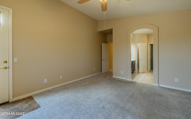 carpeted spare room with ceiling fan and vaulted ceiling