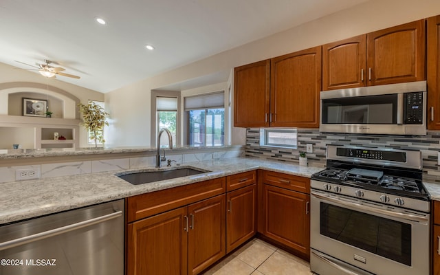 kitchen featuring light stone countertops, appliances with stainless steel finishes, backsplash, sink, and light tile patterned floors