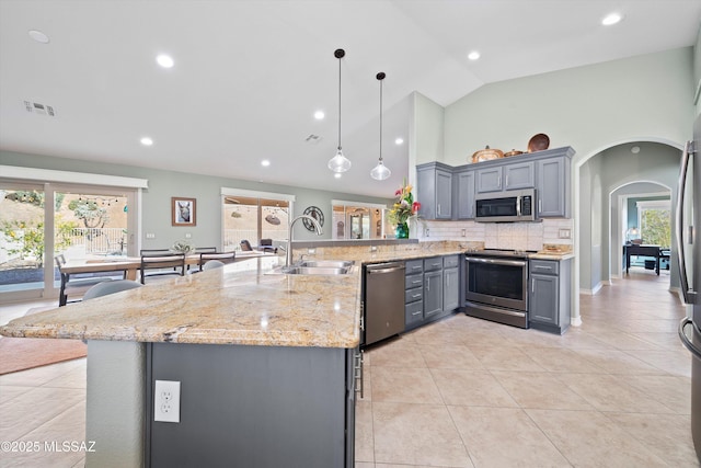 kitchen featuring arched walkways, gray cabinetry, stainless steel appliances, a peninsula, and a sink