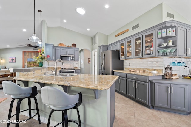 kitchen featuring gray cabinetry, a sink, appliances with stainless steel finishes, a peninsula, and lofted ceiling