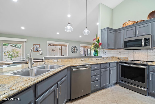 kitchen with light tile patterned floors, stainless steel appliances, a sink, gray cabinets, and tasteful backsplash