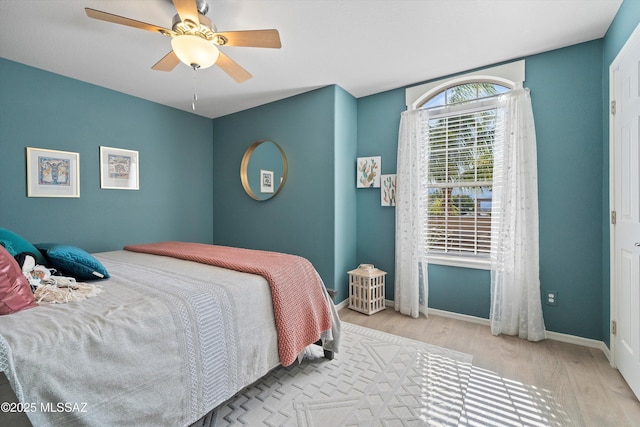 bedroom featuring ceiling fan, baseboards, and wood finished floors