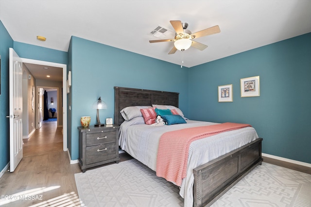 bedroom featuring visible vents, ceiling fan, baseboards, and wood finished floors