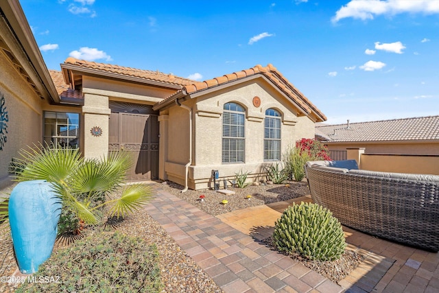 exterior space featuring a tiled roof and stucco siding