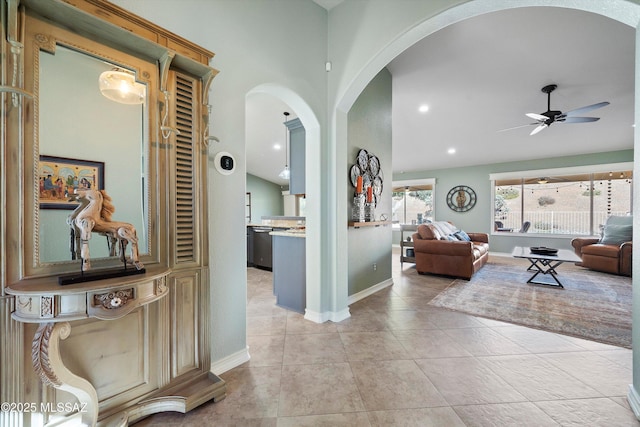 corridor with light tile patterned floors, recessed lighting, arched walkways, and baseboards