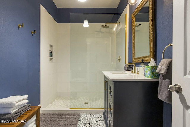 bathroom with a tile shower and vanity