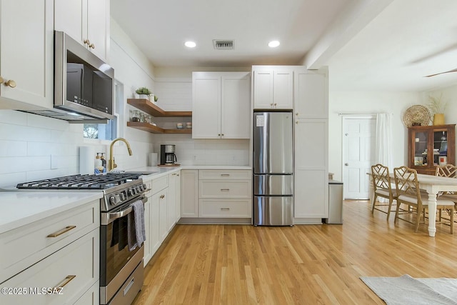 kitchen featuring tasteful backsplash, white cabinetry, sink, and appliances with stainless steel finishes