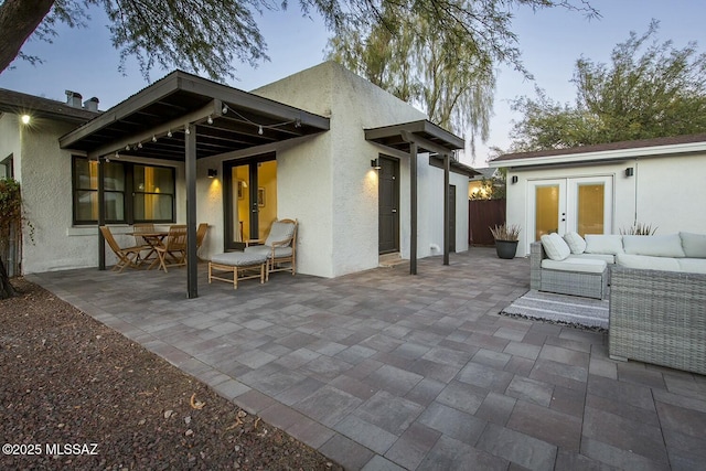 back house at dusk with outdoor lounge area, french doors, and a patio