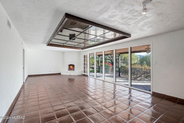 unfurnished living room featuring baseboards, a large fireplace, visible vents, and tile patterned floors