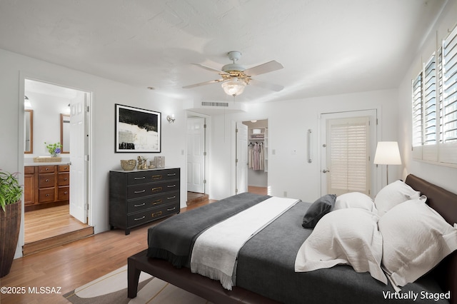 bedroom featuring a walk in closet, connected bathroom, ceiling fan, light wood-style flooring, and visible vents