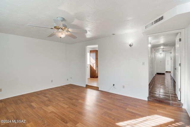 unfurnished room with ceiling fan, visible vents, and wood finished floors