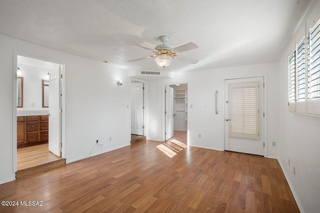 unfurnished bedroom featuring ensuite bath, ceiling fan, a spacious closet, light hardwood / wood-style flooring, and a closet