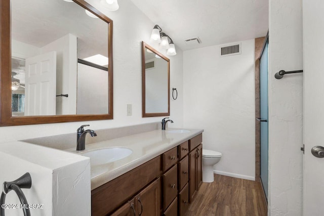 bathroom featuring visible vents, an enclosed shower, wood finished floors, and a sink