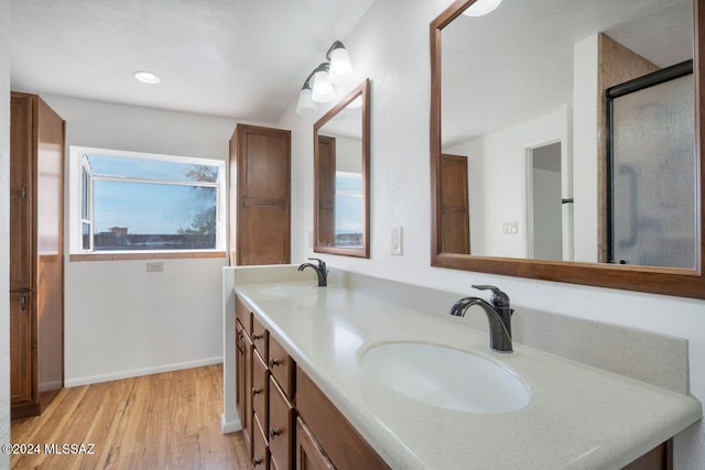 full bathroom featuring baseboards, double vanity, a sink, and wood finished floors