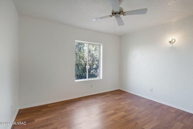 unfurnished room with baseboards, wood finished floors, and a ceiling fan