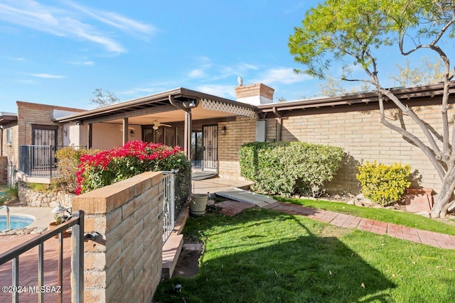 ranch-style home featuring brick siding, a front lawn, ceiling fan, and a chimney