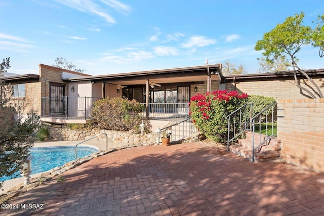 rear view of property with an outdoor pool, brick siding, ceiling fan, and a patio area