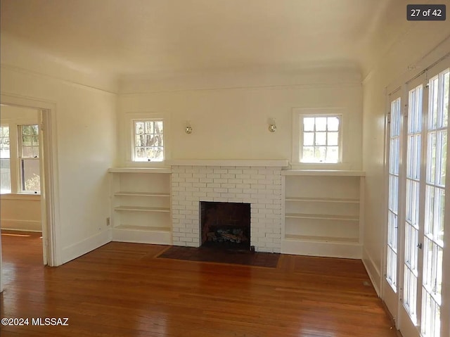 unfurnished living room featuring dark hardwood / wood-style floors and a brick fireplace