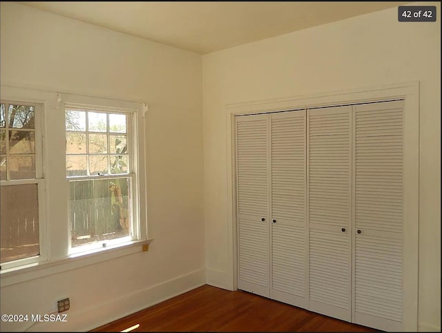 unfurnished bedroom with a closet and dark hardwood / wood-style floors