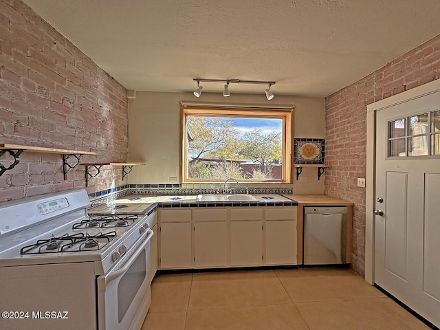 kitchen featuring tile counters, dishwasher, brick wall, white range with gas cooktop, and light tile patterned floors