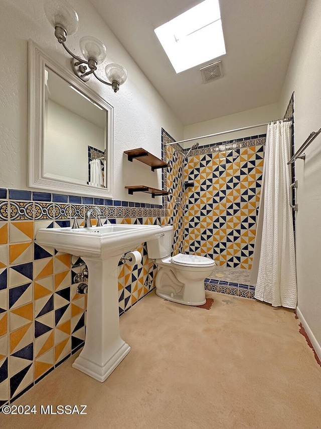 bathroom featuring a shower, a skylight, toilet, and tile walls