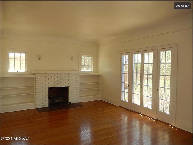 unfurnished living room with wood-type flooring and a brick fireplace