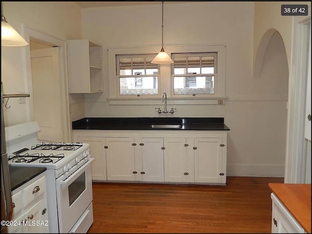 kitchen with pendant lighting, white cabinets, white gas range oven, and hardwood / wood-style flooring