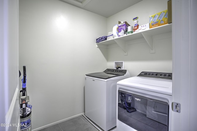 laundry room with dark tile patterned floors and washing machine and clothes dryer