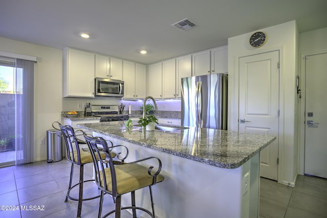 kitchen with white cabinets, stainless steel appliances, and a kitchen island with sink