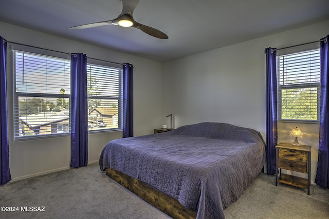 bedroom with ceiling fan, light carpet, and multiple windows