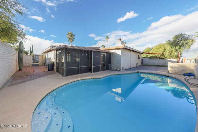 view of swimming pool featuring a patio area and a sunroom