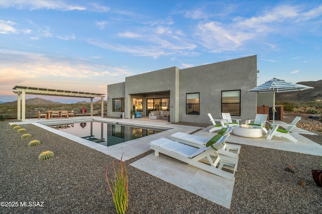 back of house with an outdoor living space with a fire pit, a mountain view, and a patio