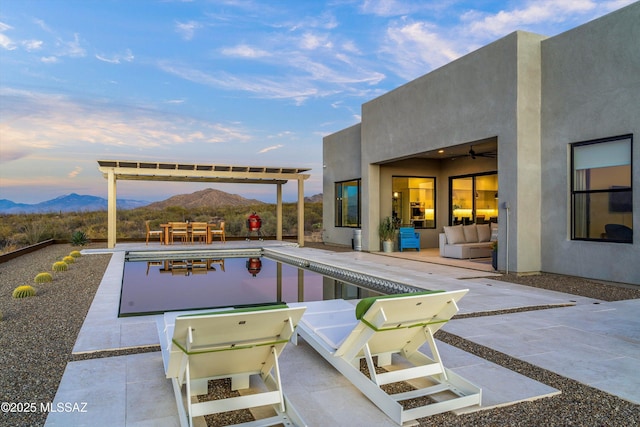 pool at dusk featuring a patio area, a mountain view, and an outdoor hangout area