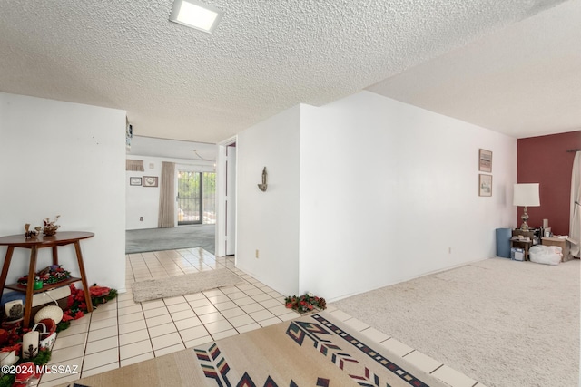 hall featuring light tile patterned flooring and a textured ceiling