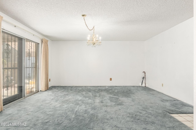 carpeted empty room featuring a textured ceiling and an inviting chandelier